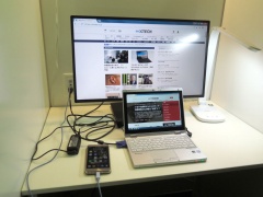 室内のテーブル（左）と、実際にPCやスマートフォンを置いて作業している様子（右）。液晶ディスプレーは27型だ