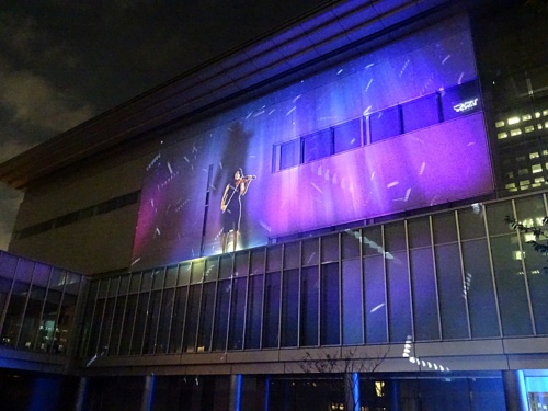 図1　品川で演奏するバイオリニストのライブ映像を、有明のビルにプロジェクションマッピング