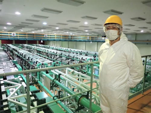 レーザー科学研究所内のレーザー装置の配管と藤岡氏(写真:日経クロステック)