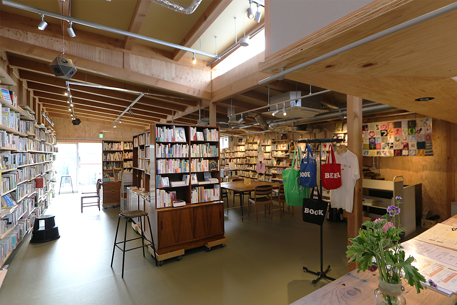 商業棟2階「本屋 B&B」（11）陳列スペース。現在は、オンライン配信を併用する格好としているが、書籍著者のトークイベント開催と飲食サービスをビジネスの一翼とする新刊書店であるため、可動式書棚の並ぶフレキシブルな空間とされている（写真：日経アーキテクチュア）