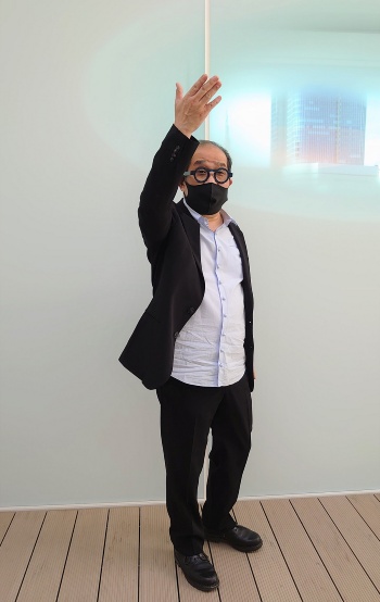 ASを共同主宰するパートナーの青木淳氏。屋上で建物の特徴を説明しているところ(写真:日経クロステック)