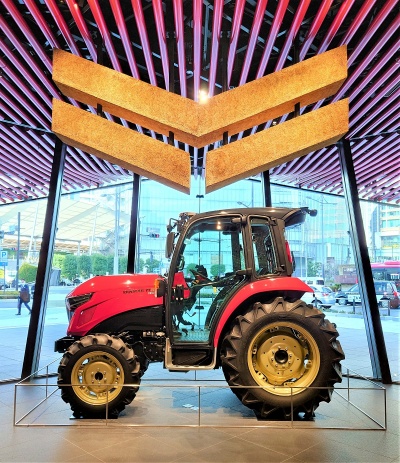 建物正面のエントランス空間には、ヤンマーの象徴である赤いトラクターと、稲わらでつくったロゴマーク「FLYING-Y」を設置した(写真:日経クロステック)