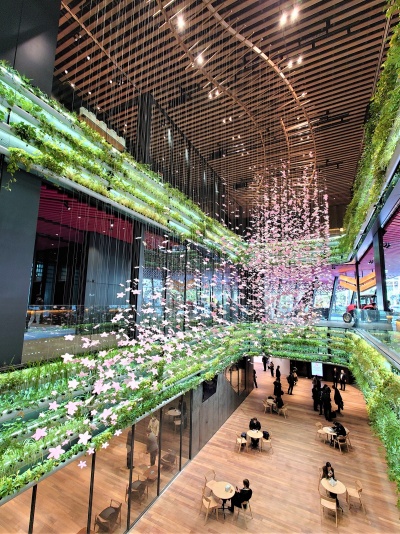 吹き抜けをルーバー型の水耕栽培緑化システムで囲んだ。桜の花びらを模した無数のオブジェを天井からつるし、ヤンマー創業時からの価値観「HANASAKA(ハナサカ)」を形で表現した。花びらは佐藤氏がデザインしたヤンマーのロゴマークの組み合わせで出来ている(写真:日経クロステック)