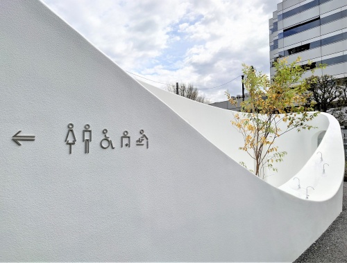 歩道に面する建物の手前(西側)部分は、中央がへこんだカーブを描いている。幾つもの蛇口が並ぶ大きな手洗い場だ。樹木も植えた(写真:日経クロステック)