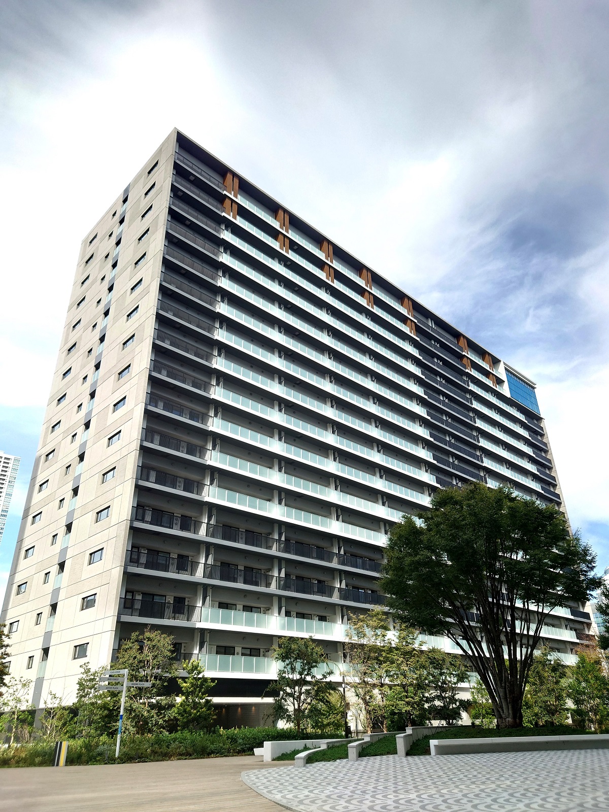 街区中央の中庭空間から見たB棟。右上の青い部分が2層ガラス張りのペントハウス。1階の向かって右側が保育施設で、その手前に園庭がある（写真：日経クロステック）