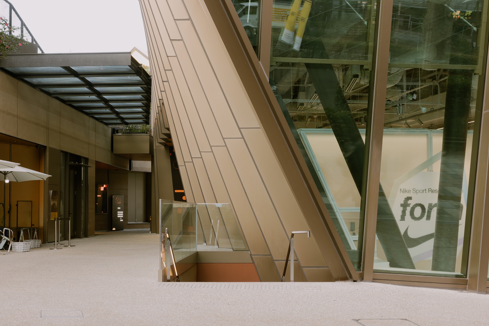 表参道からそのまま階段（中央部）を下りて地下階のホールや食堂に行けるようにした。右手のガラス張りの店舗は「NIKE HARAJUKU」（写真：日経クロステック）