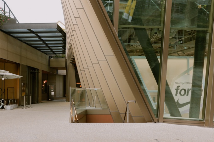 表参道からそのまま階段(中央部)を下りて地下階のホールや食堂に行けるようにした。右手のガラス張りの店舗は「NIKE HARAJUKU」(写真:日経クロステック)