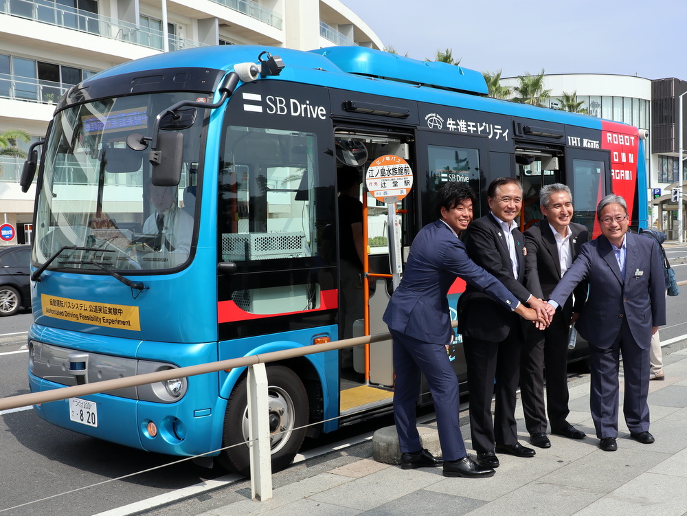 新江ノ島水族館前で自動運転バス試乗の記念撮影に応じる黒岩祐治知事（左から2人目、2019年8月21日）