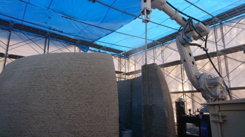 セメント系建設3Dプリンターで建屋の壁面を現場で印刷している様子。専用モルタルを吐出し堆積する（写真：會澤高圧コンクリート）