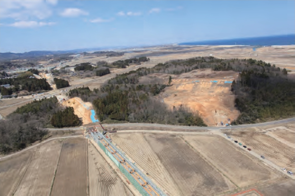 南から見た犬塚遺跡の遠景。写真左が遺跡発見のきっかけになったJR常磐線移設の工事現場、右が日建の土砂採取現場（写真：山元町）