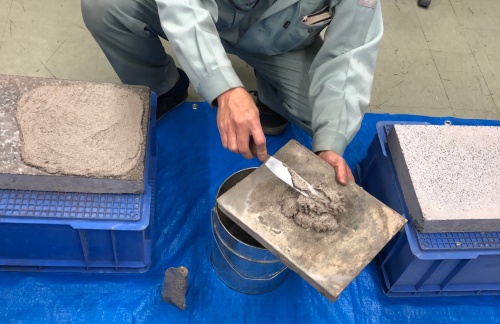 興和が販売する常温硬化型ジオポリマー系補修材「GP MONDO K」をコンクリートの表面に塗っている様子(写真:興和)