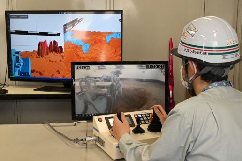 奥のディスプレーが「DeepX GeoViz for Caisson」の表示画面。ニューマチックケーソン工法で地山を掘削する重機を遠隔から操縦する際、作業員が任意の視点でショベルの刃先や地山を確認できる。手前のディスプレーは現場に取り付けたカメラによる映像。写真は茨城県つくば市にあるオリエンタル白石の拠点での模擬施工の様子（写真：日経クロステック）