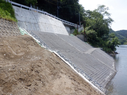 補強工事を実施した後のもたれ式擁壁。擁壁に鉄筋を挿入して背面の岩盤に固定するとともに、ブロックマットで基礎部分を根固めした(写真:岡山市)