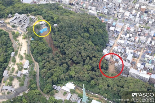 松山城がある勝山の北東側斜面が2024年7月12日に崩壊し、山麓の住宅地(赤線で囲んだ部分)が被災した。斜面上方の城内の道路(黄色い線で囲んだ部分)でも24年7月1日に路面の亀裂などの異変が起こっていた。写真左端は国指定の重要文化財を含む松山城の建築群(写真:パスコ/国際航業)