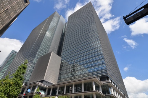 東京・大手町に8月完成した「大手町プレイス」を南東側から見上げる。写真奥が地下3階・地上35階建てのウエストタワー、手前が地下3階・地上32階建てのイーストタワー。2棟を低層部で連結する構造だ。外装にみられる水平庇やアルミ丸柱は、以前この地にあった逓信ビルの意匠を意識したもの(写真:日経アーキテクチュア)