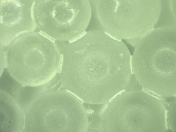 二酸化ケイ素を主成分とするガラスビースとアルコール、触媒を加熱して製造した硬化体を顕微鏡で見る。左の写真では粒子と粒子を接着している状況がわかる。右の写真は、粒子の隙間に接着成分が入り込んで一体化した状態(写真:東京大学酒井雄也研究室)