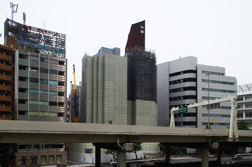 建物正面を走る東京高速道路の高架越しに中銀カプセルタワービルを見る。右が13階建てのA棟で、左が11階建てのB棟。B棟は塔屋が撤去済みだ（写真：安川 千秋）