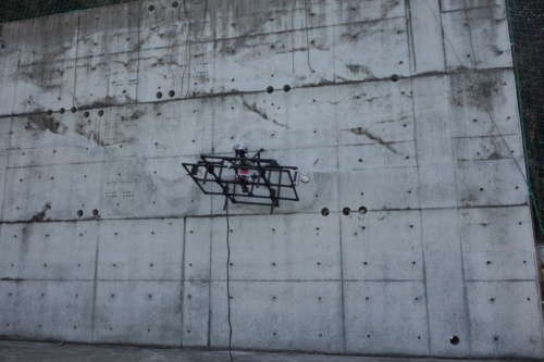 ドリルを搭載した「接触・微破壊式ドローン」がコンクリートの壁面に穴を開ける様子（写真：建築研究所、東京理科大学、西武建設）