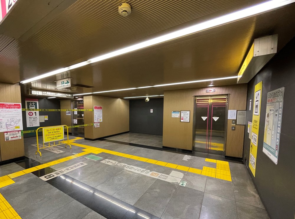 地下鉄六本木駅地下5階のエレベーター前の様子。写真右が故障した2号機。地下1階と地下5階を結ぶもので、復旧済み。写真左が停止中の3号機で、テープと柵で閉鎖している。2023年2月1日撮影（写真：日経クロステック）