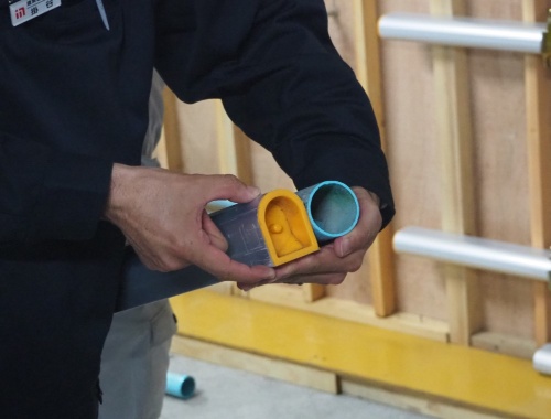 黄色いキャップが付いているのが新型のアルミパイプで、断面形状は円形ではなくかまぼこ形になっている。丸久が開発を主導した。右が従来の鋼製パイプ(写真:日経クロステック)