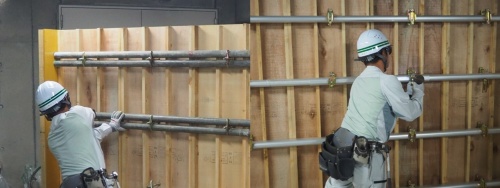 フォームタイを取り付ける様子。左が在来工法で、鋼製パイプを片手で支えながら施工する必要があった。右が新工法で、フォームタイの下のボルトにパイプを預けられるため、両手で施工できる(写真:日経クロステック)