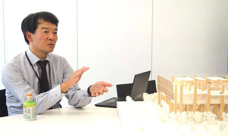 新・本店ビルの木造部分を説明する、三菱地所設計の吉原正構造設計部長（写真：日経クロステック）