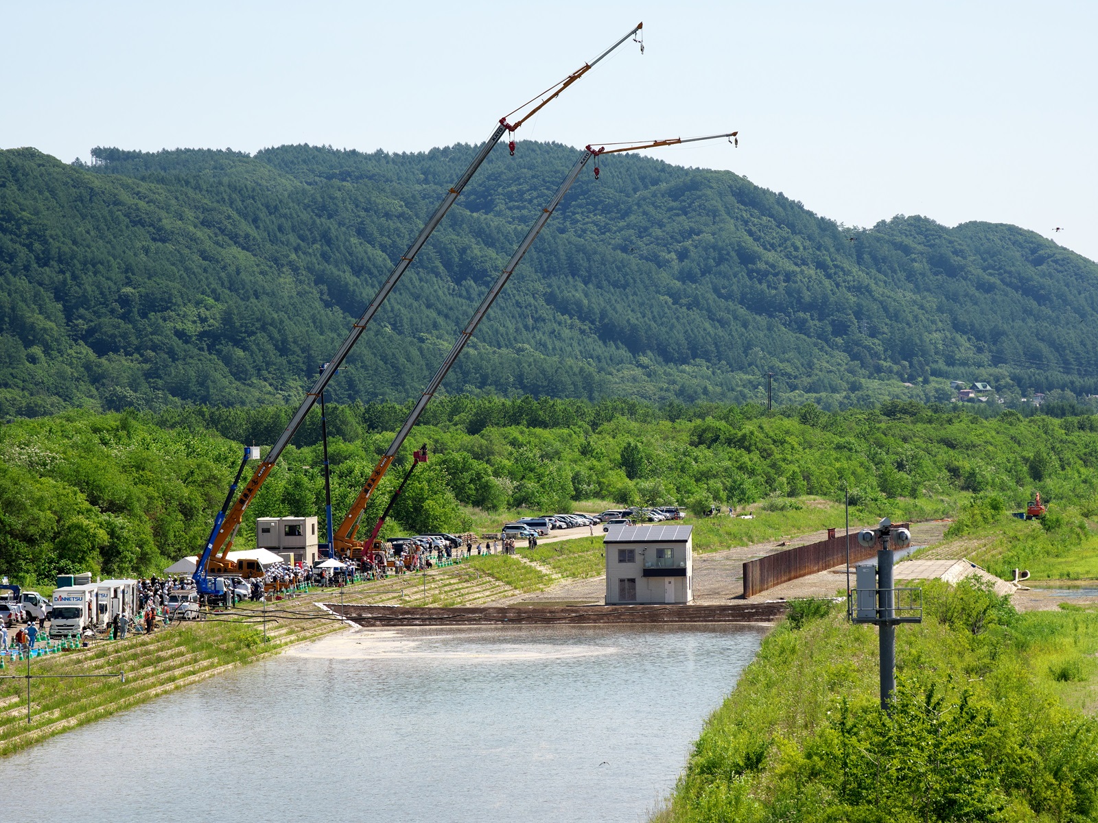 上流側から見た実験現場。実験水路に総2階建ての木造住宅を建設した。住宅の手前が堤防試験体だ（写真：池谷 和浩）