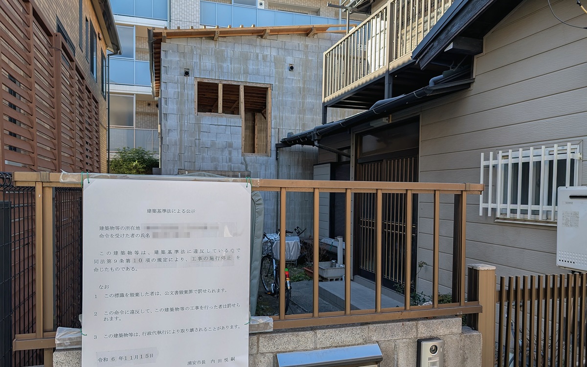 2階建ての母屋の奥に立つのが問題の構造物。2024年11月に浦安市が施工停止命令を出したが、その後も工事が続いた。2025年2月10日撮影（写真：池谷 和浩）