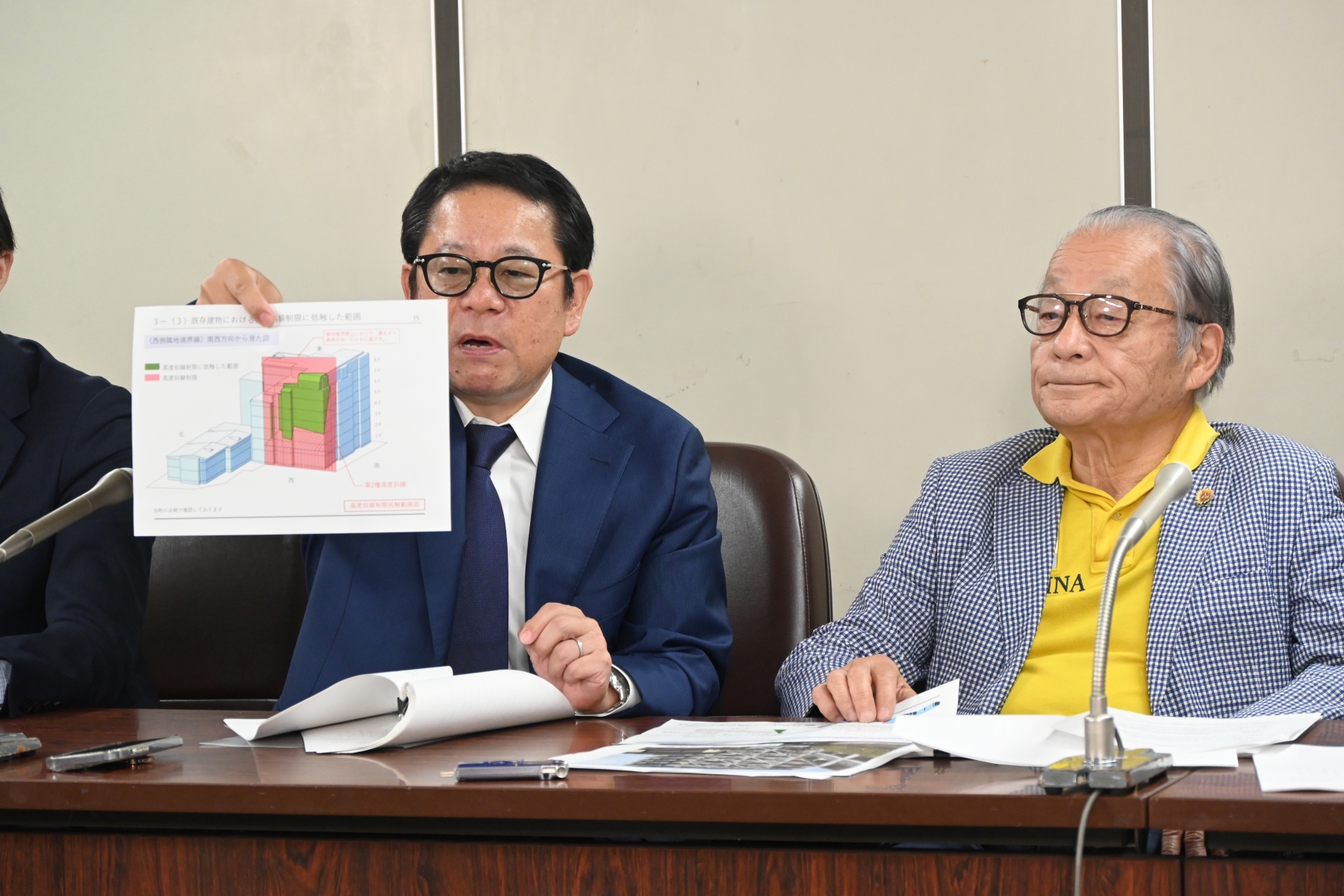原告の1人で管理組合理事長の三身太郎氏（左）。2025年6月4日の提訴後の記者会見で、資料を手にマンションの欠陥を説明した（写真：日経クロステック）