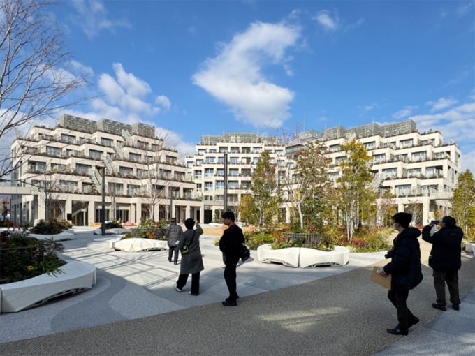 コートヤードを囲むように住居棟が立つ。植栽を囲う白いベンチは建設3Dプリンターで制作した(写真:日経クロステック)