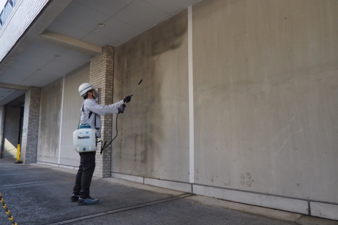 「DAC(ダック)コート」を東京都品川区第3庁舎の耐震壁の一部に噴霧塗装した。白線の左側に塗布し、塗布していない右側と比較しながら3年間経過を見る。2026年3月5日撮影(写真:日経クロステック)