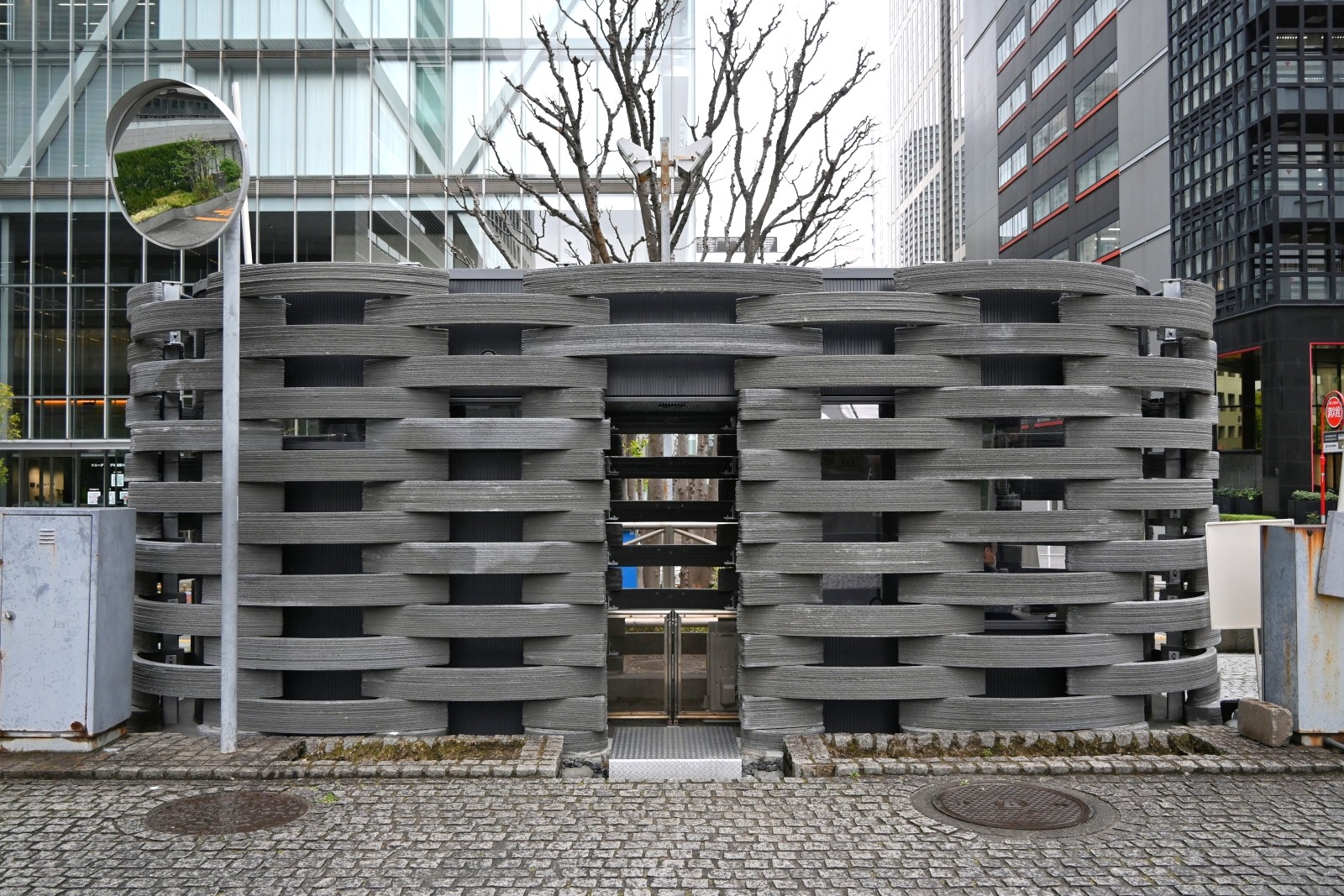 NTTデータがNTTファシリティーズ、Polyuseと共同で改修したビル「NTT品川TWINS」の警備棟。建物の周囲に3Dプリンターで製作した弓形の部材を積み上げた（写真：日経クロステック）