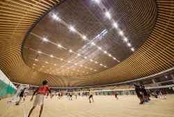 バスケットボールのコート4面分の広さがあるメーンフロア。静岡県の天竜スギによる256本の集成材が、楕円状に並んで上屋根を支える。天井ルーバーの上に、総重量2350トンの鉄骨トラスの上屋根がある（写真：吉田 誠）