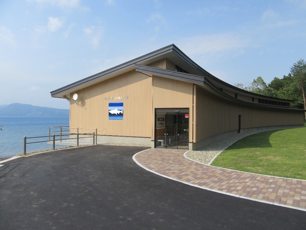 田沢湖畔に7月1日にオープンした「田沢湖クニマス未来館」。山梨県で捕獲した個体を水槽展示する。木造平屋建て、延べ面積687m2。当初案では同793m2だったが、減額のため規模を縮小した（写真：仙北市）