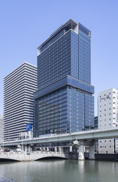 2024年4月に竣工した「大阪堂島浜タワー」（中央の青い建物）。旧大阪三菱ビルを建て替えた。中層部のオフィスはワンフロアが約530坪の無柱空間になる。川沿いに位置するため、水害に備えて電気施設は地上3階以上に配置する（写真：三菱地所、三菱商事都市開発、積水ハウス、三菱HCキャピタル）
