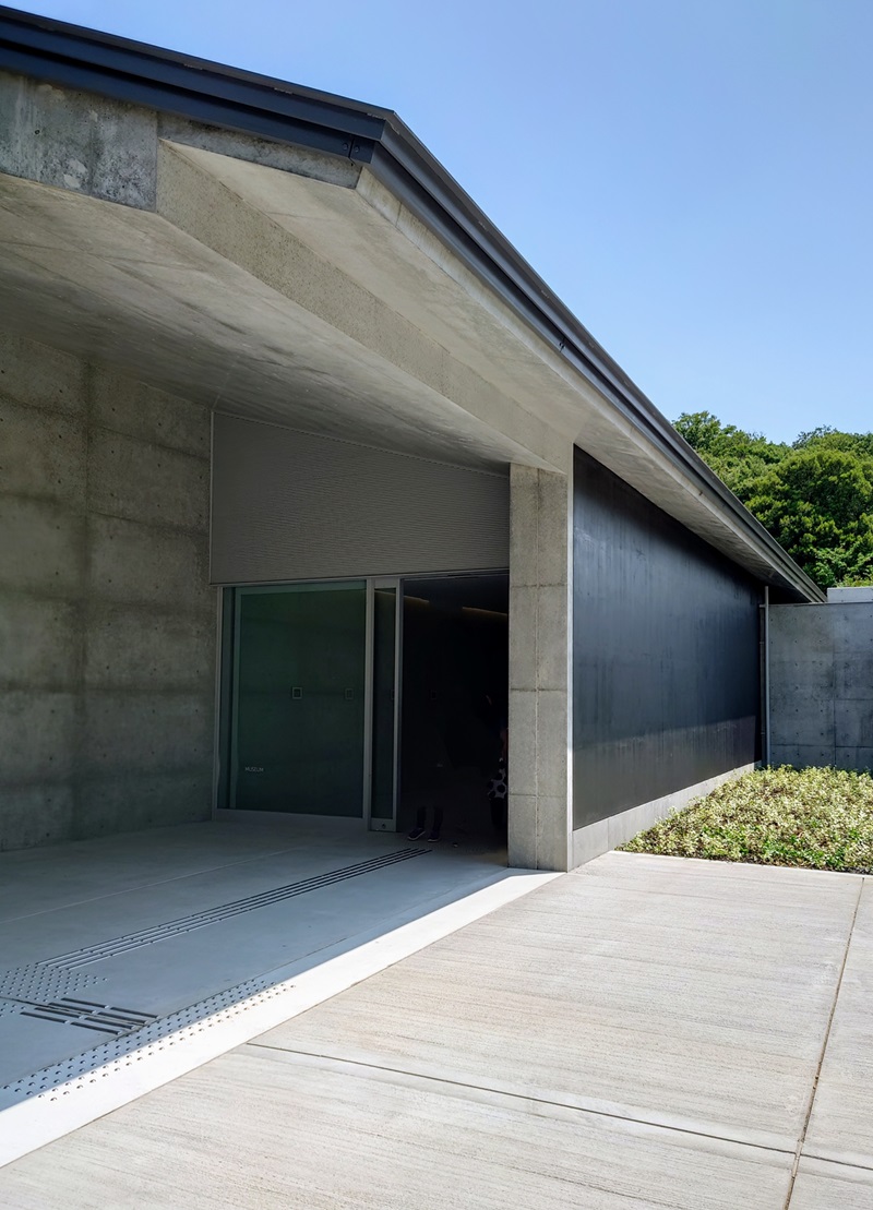 展示室に続くガラス扉。黒しっくいで仕上げた外壁は集落の外壁に使われている焼き杉をイメージしたもの（写真：日経クロステック）