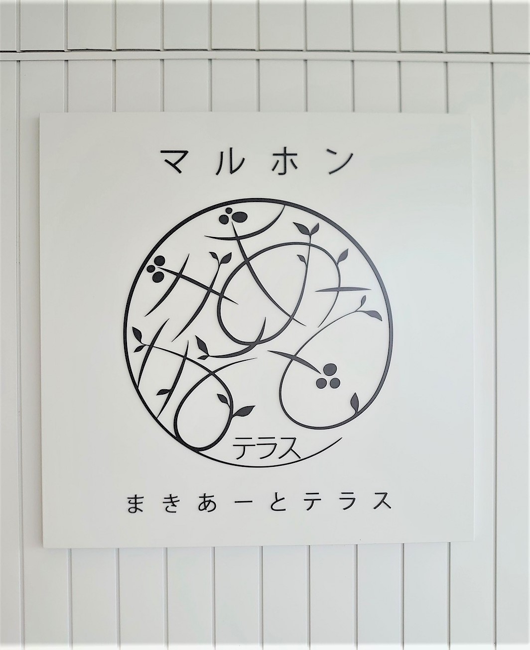 施設のサイン。マルホンは、建物の施工者の1社である地元の丸本組が取得した命名権（ネーミングライツ）によるもの。まきあーとは施設の愛称を募集して選ばれた、石巻の「まき」と芸術の「アート」を組み合わせた言葉だ（写真：日経クロステック）