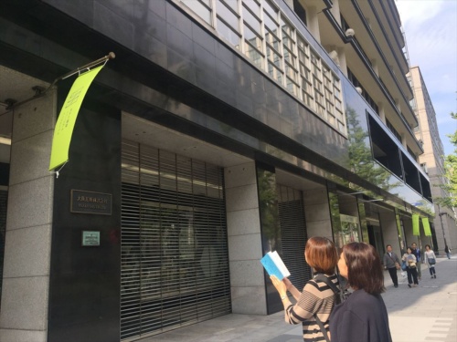 19年のガイドブックは水色の表紙。参加者はこれを手に建物を見て回る。写真は大阪ガスビルで、参加建物は黄緑色のバナーを掲げている（写真：長井 美暁）