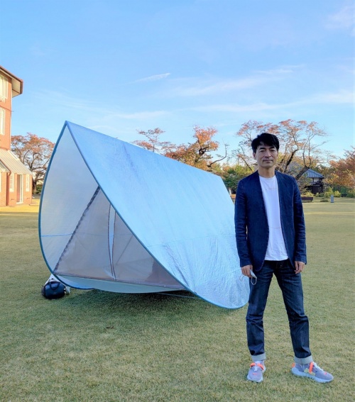 タトアーキテクツの島田陽氏がデザインした半円形のテント。円を2つ折りにしたフレームの中に、正三角形の筒を入れてつった。地面から少し浮かせ、凹凸がある場所でも快適に過ごせるようにしている。中に入り、ハンモックのように揺らして遊ぶことができる（写真：日経クロステック）