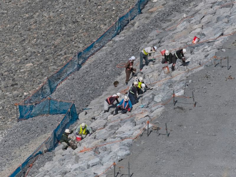 Q．市街地に程近い現場、傾斜した石の上で何をしている？