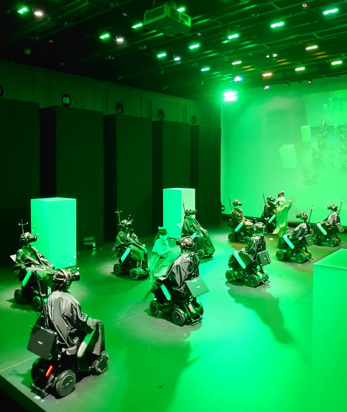 電動車椅子の列の間をダンサーが踊りながら走り抜ける。このシーンは、ヘッドマウントディスプレー（HMD）をかぶった体験者にどう見えているのか。この記事では極力、ネタばらしはしない。なお、写真や画像は全て本番前のもの（写真：日経クロステック）
