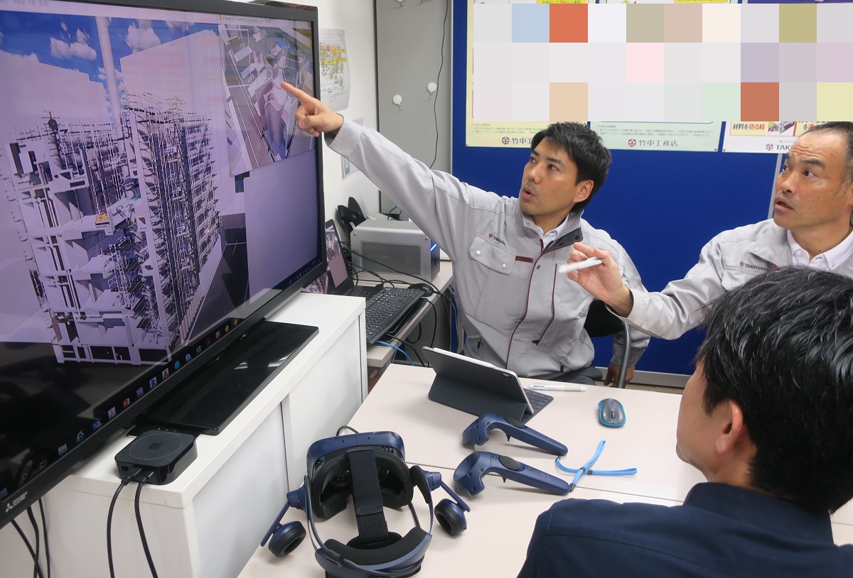 作業所長の永井一嘉氏（右）と課長 工事担当の砂川亮馬氏（左）。BIMの画面を見ながら、施工手順などを検討する日々が続いている。手前は今回の建物の設計者。施工で利用するBIMの元データは、設計チームからシステムを介して引き継いでいる（写真：日経アーキテクチュア）