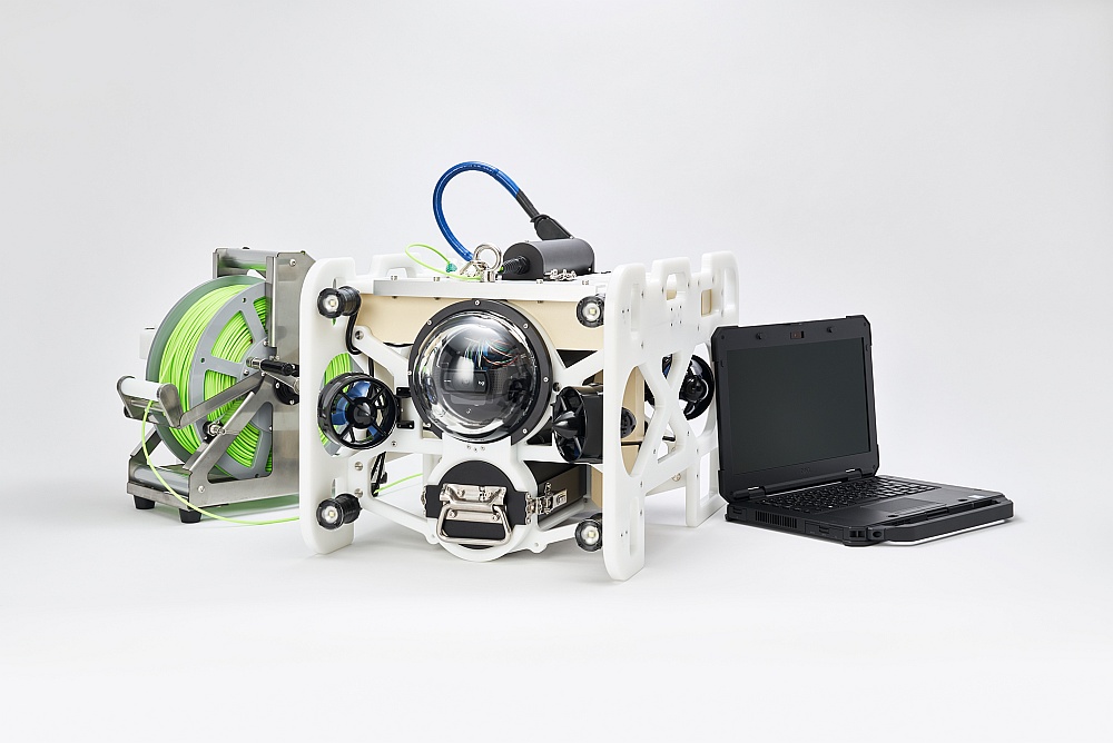 開発した「DiveUnit300」と専用の光ファイバーのケーブル、処理用のパソコン。機体は1台数百万円となる見込みで、販売の他にレンタルも実施する。ケーブルは独自技術で水と同じ比重を実現。浮きも沈みもしないので、水中ドローンの動作の邪魔にならない。耐久性が高い高強度繊維を採用した。1.5kmの長さで約20kgと軽く、持ち運びが容易だ（写真：フルデプス）