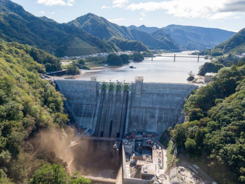 台風19号が通過した後の10月13日午後2時に撮影した八ツ場ダム。利水放流管から泥混じりの水が噴き出し、土煙を上げる。堤体上空でのドローン飛行は許可が必要なため、許可が不要なダム下流の吾妻峡からドローンを離着陸させて撮影した(写真:大村 拓也)