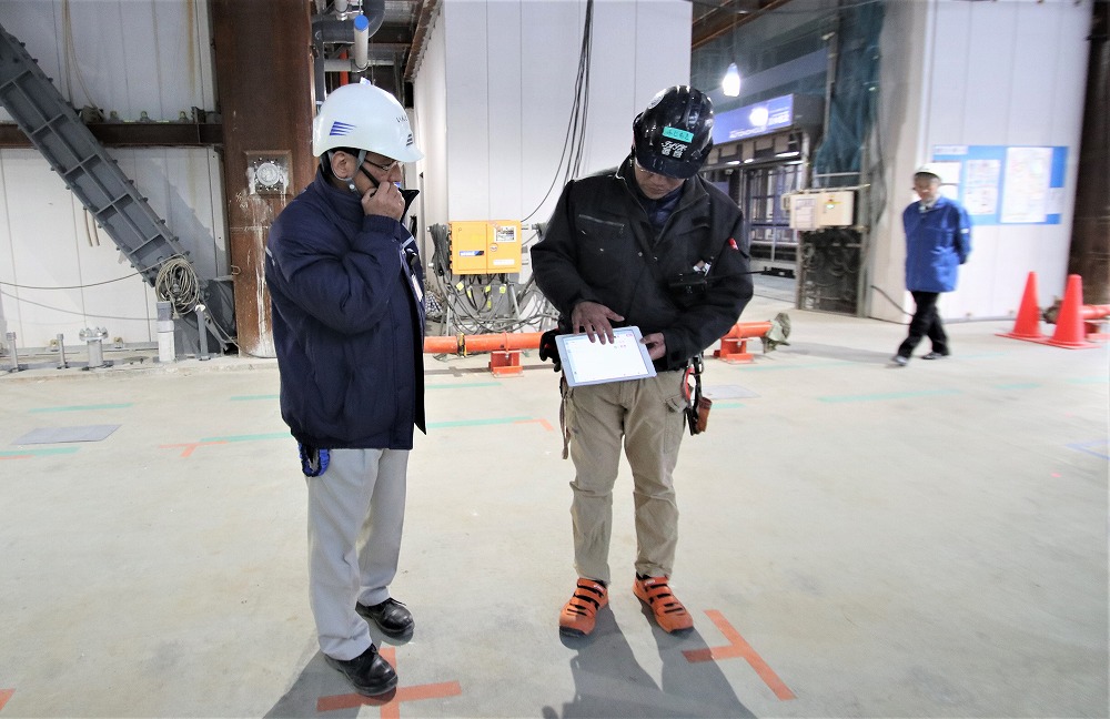 からくさホテルグランデ新大阪タワーの現場では、揚重専門会社のロボットオペレーター（写真右）がiPadで搬送を指示した（写真：日経アーキテクチュア）