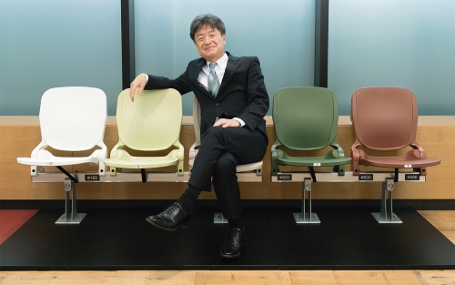 梓設計の杉谷文彦社長。オフィス入り口には、国立競技場の観客席の原寸大模型を展示している(写真:的野 弘路)