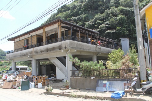 坂本地区に立つピロティ形式の2階建て住宅Fでは、ボランティアがバルコニーや2階の床上にたまった泥を取り出す作業を行っていた。2020年7月19日に撮影（写真：日経クロステック）