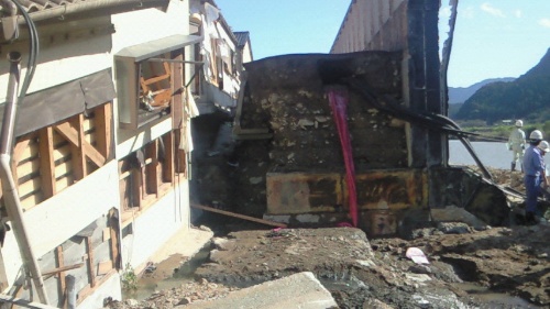 相野谷川沿いの左岸側に立つ高岡地区の輪中堤が壊れた現場。輪中の中に水がたまった状態で川側の水位が下がった際に直立壁の一部が川側に転倒してこのような状態になった。右側の相野谷川の水面が見える部分には転倒した輪中堤があった(写真:国土交通省近畿地方整備局)