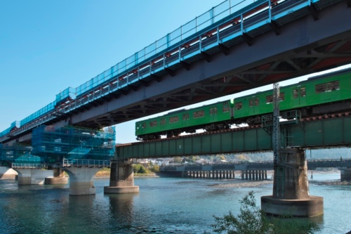 複線化に伴い、上り線の新設工事をしている宇治川橋梁。奥に見える既存の線路を電車が行き交う（写真：生田 将人）