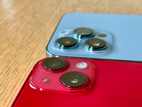 iPhone 13のカメラはiPhone 12に比べると出っ張りが増しているが、iPhone 13 ProやiPhone 13 Pro Maxほどは出っ張っていない。写真の奥はiPhone 13 Pro Max